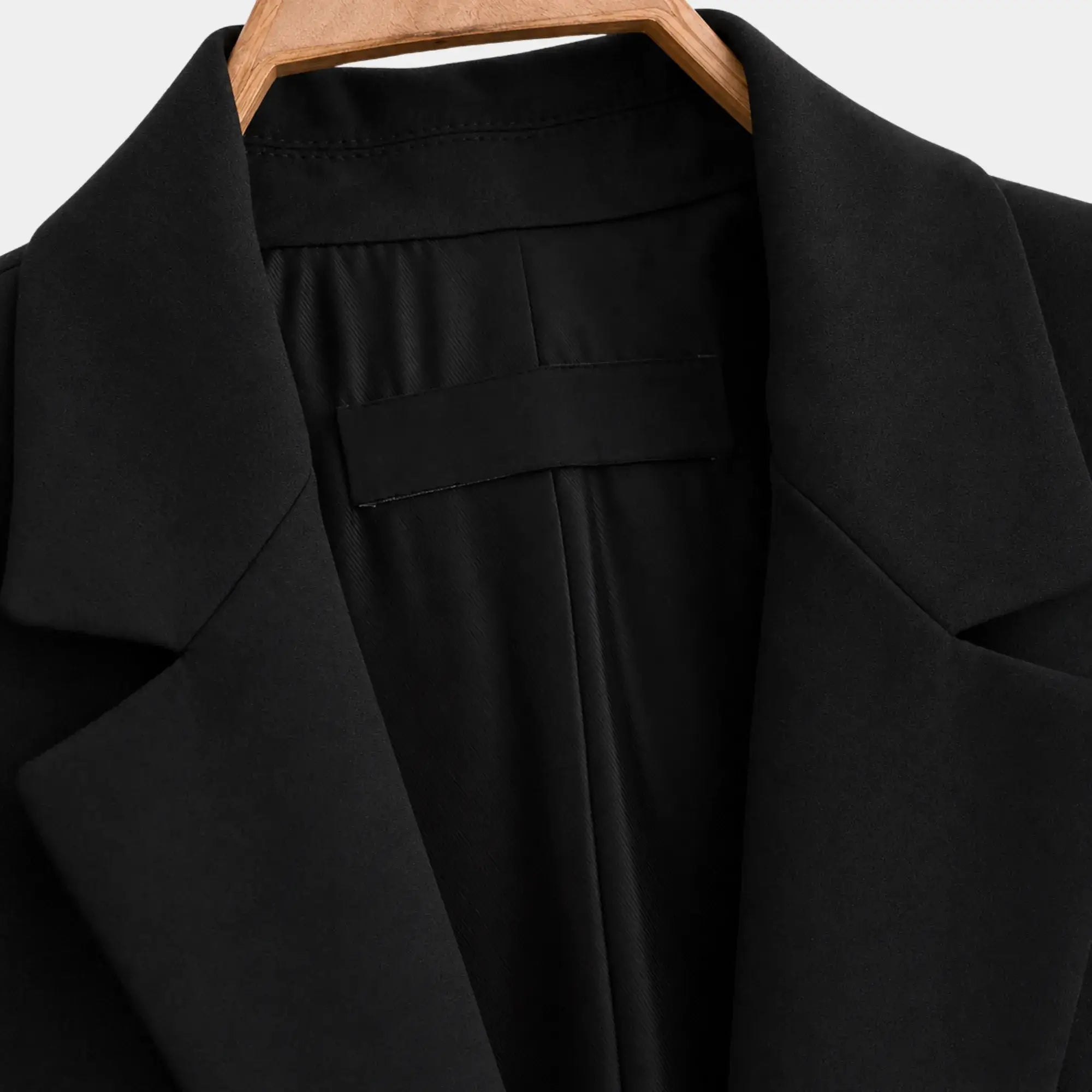 Detalhe do forro interno e da lapela do blazer feminino preto de alfaiataria com acabamento refinado.