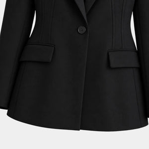 Detalhe frontal do blazer feminino preto de alfaiataria com botão único e bolsos decorativos.
