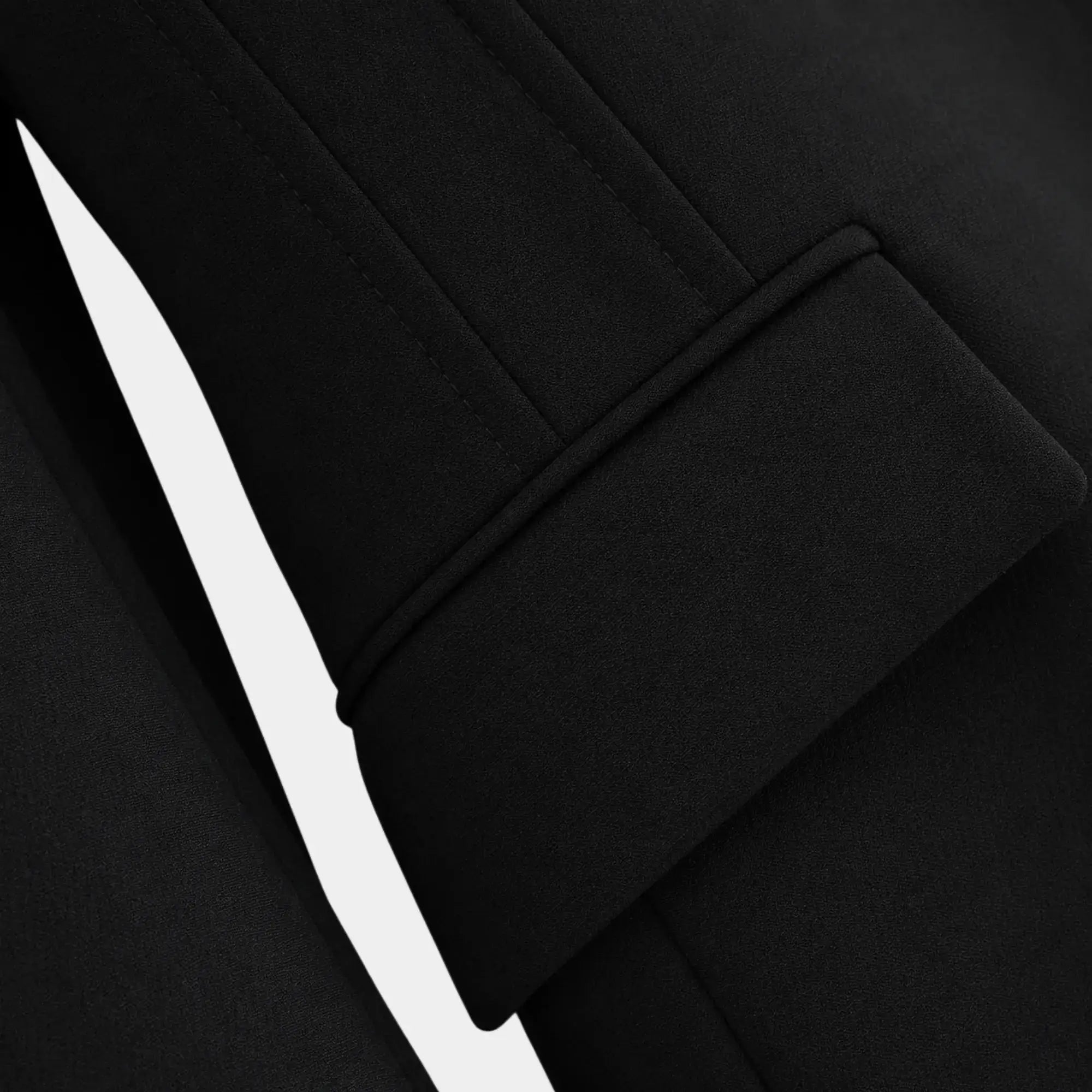 Detalhe do punho dobrado do blazer feminino preto de alfaiataria com acabamento refinado.