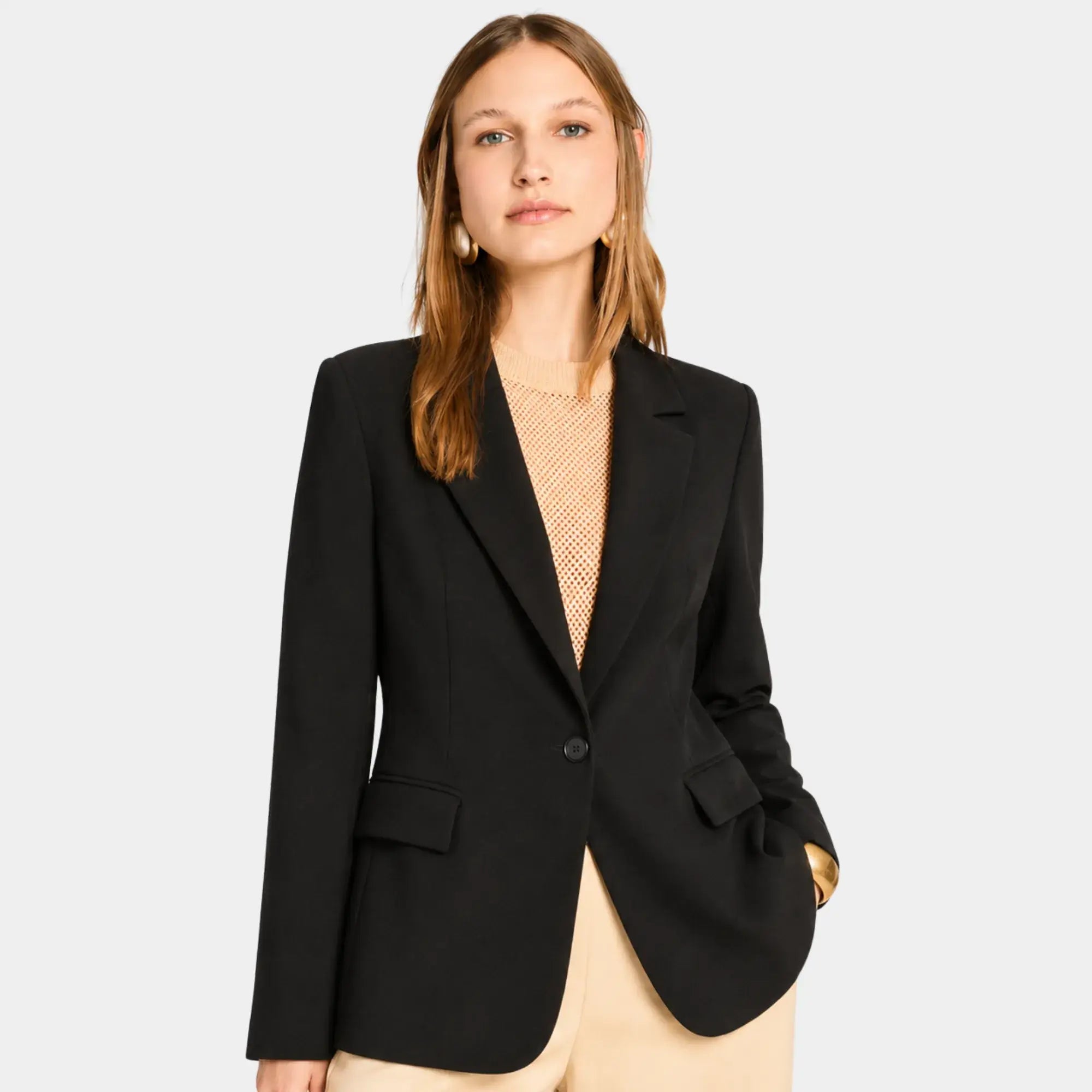 Mulher usando blazer feminino de alfaiataria preto acinturado com lapela clássica e caimento elegante.