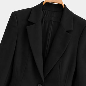 Detalhe da lapela ampla e acabamento interno do blazer feminino preto de alfaiataria.