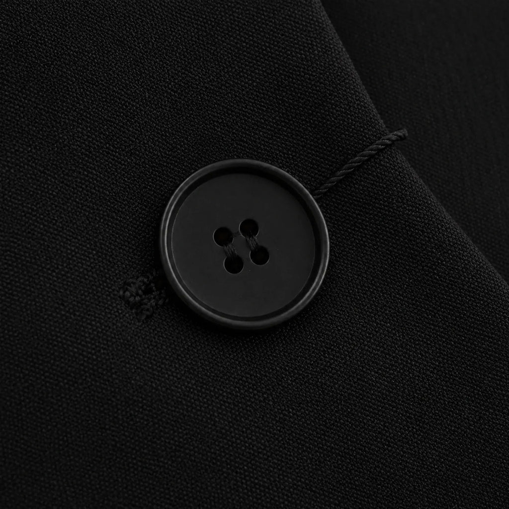 Detalhe do botão de fechamento do blazer feminino preto de alfaiataria com acabamento refinado.
