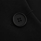 Detalhe do botão de fechamento do blazer feminino preto de alfaiataria com acabamento refinado.