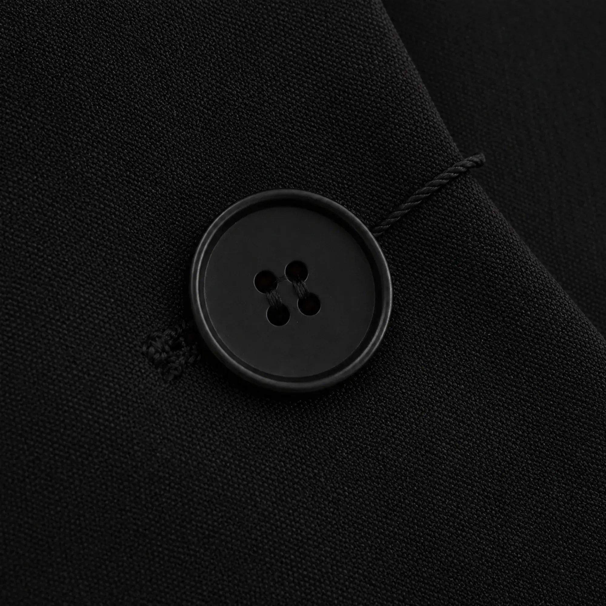Detalhe do botão de fechamento do blazer feminino preto de alfaiataria com acabamento refinado.