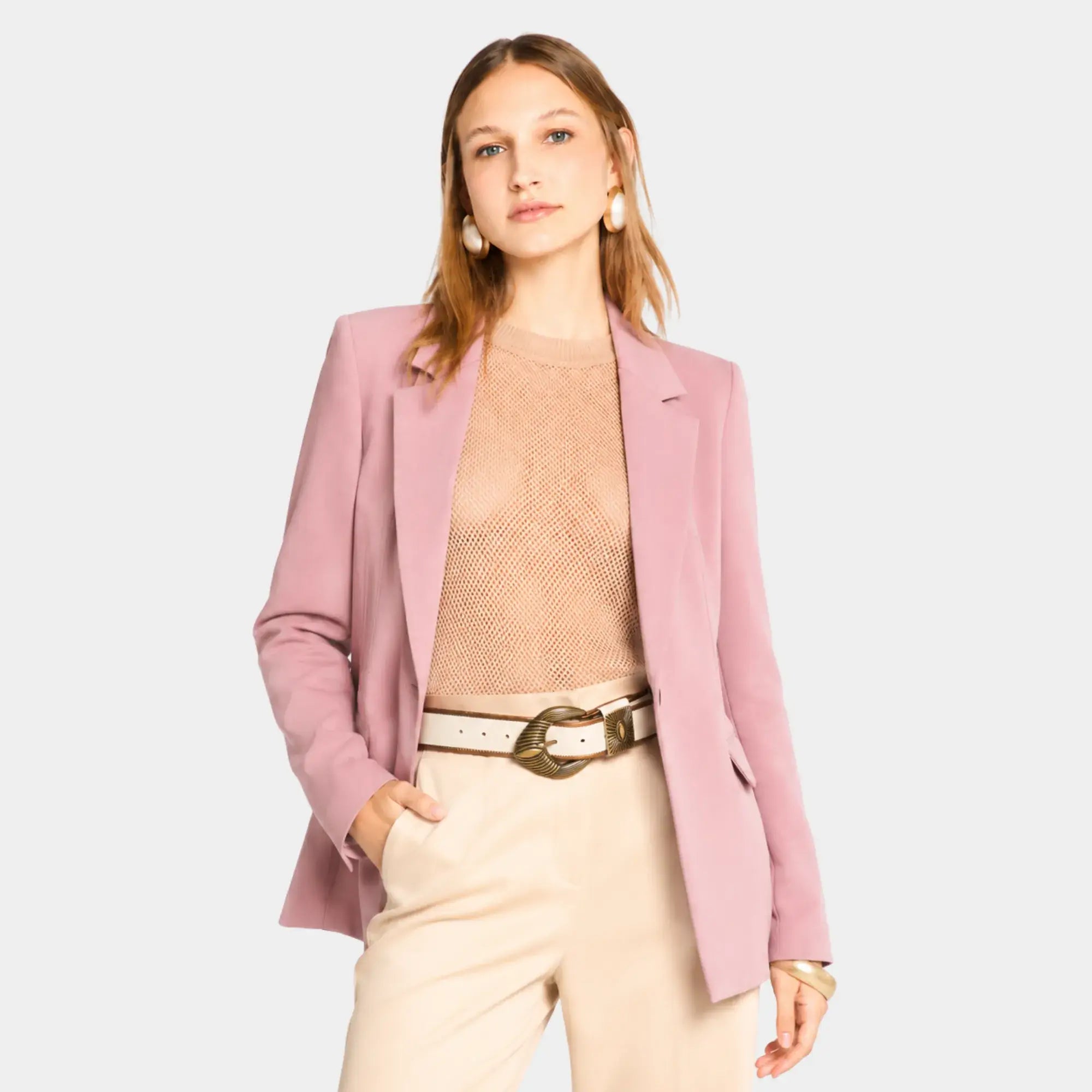Mulher usando blazer feminino rosa de alfaiataria aberto com calça de cintura alta e visual elegante