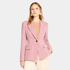 Mulher usando blazer feminino rosa de alfaiataria acinturado com botão único e calça clara elegante