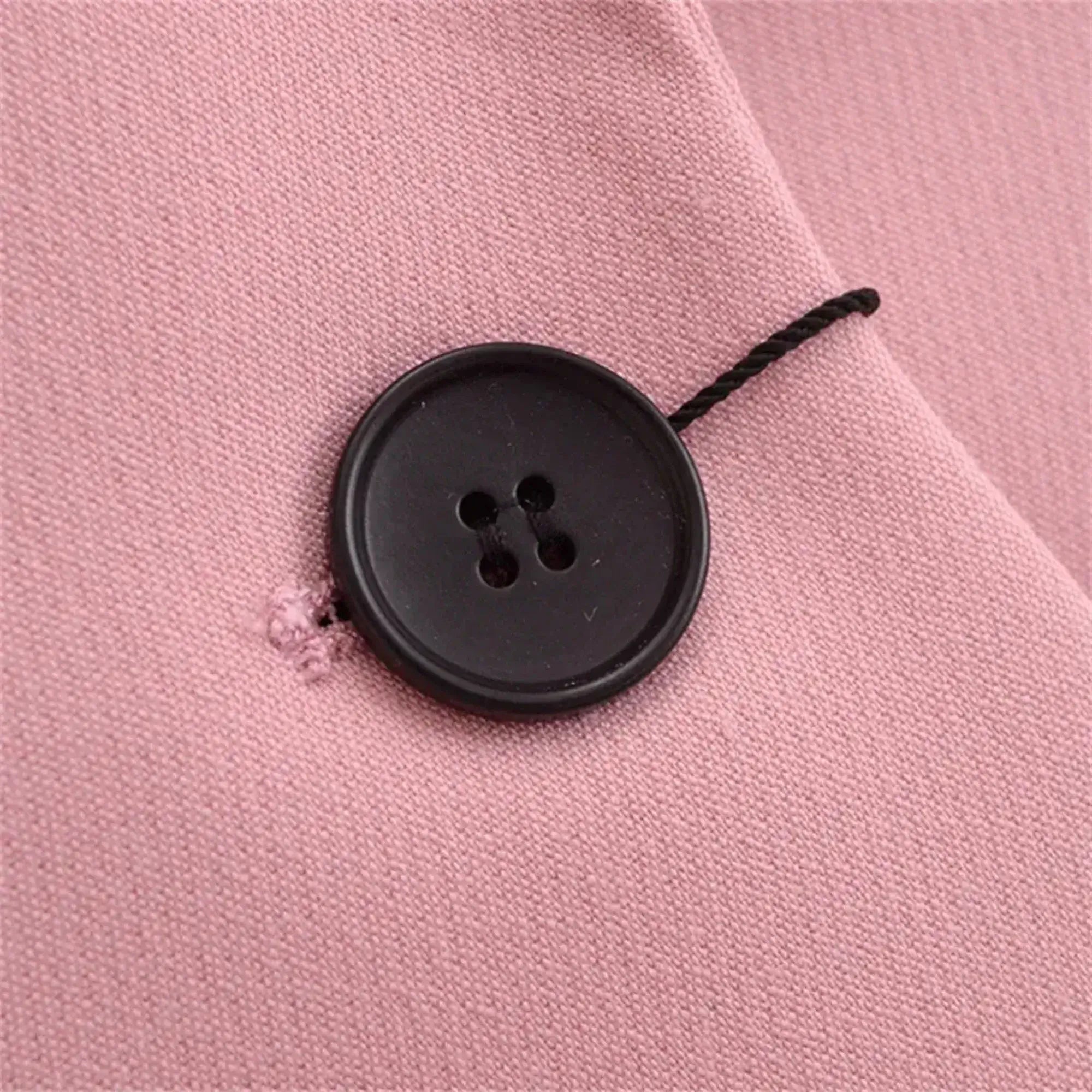 Detalhe do botão frontal em blazer feminino rosa de alfaiataria com acabamento elegante