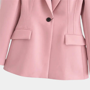 Detalhe dos bolsos com lapela e fechamento por botão único em blazer feminino rosa de alfaiataria