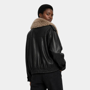 Mulher usando jaqueta preta oversized com gola de pelo removível em estilo clean luxury
