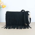Bolsa crossbody de camurça preta com franjas na frente e alça longa, sobre fundo claro com flores