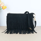 Bolsa crossbody de camurça preta com franjas na frente e alça longa, sobre fundo claro com flores