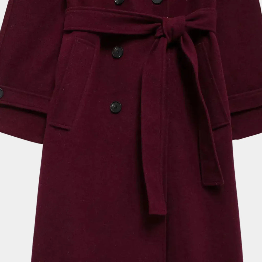Detalhe do cinto removível, bolsos funcionais e fechamento duplo do trench coat feminino longo vinho