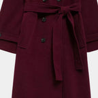 Detalhe do cinto removível, bolsos funcionais e fechamento duplo do trench coat feminino longo vinho