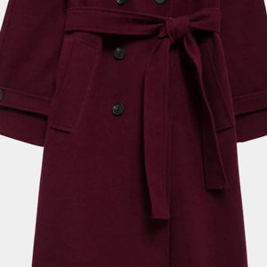 Detalhe do cinto removível, bolsos funcionais e fechamento duplo do trench coat feminino longo vinho