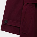 Detalhe do punho com botão, bolso lateral e acabamento premium do trench coat feminino longo vinho