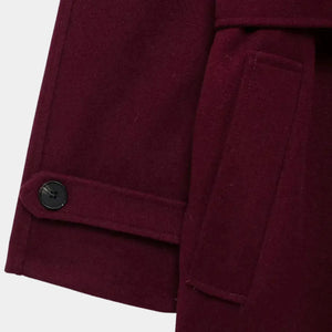 Detalhe do punho com botão, bolso lateral e acabamento premium do trench coat feminino longo vinho