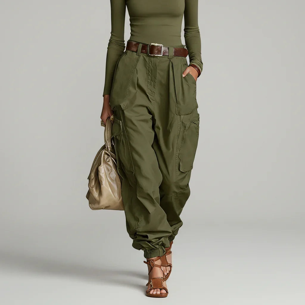 Modelo de calça cargo wide leg verde militar de cintura alta com cinto marrom, blusa verde e bolsa bege