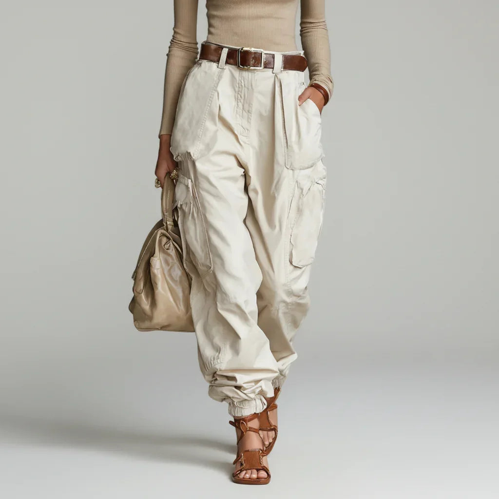 Modelo de calça cargo wide leg off white de cintura alta com cinto marrom, blusa bege e sandália rasteira