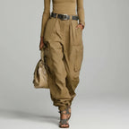Modelo de calça cargo wide leg caqui de cintura alta com cinto marrom, blusa caqui e bolsa bege