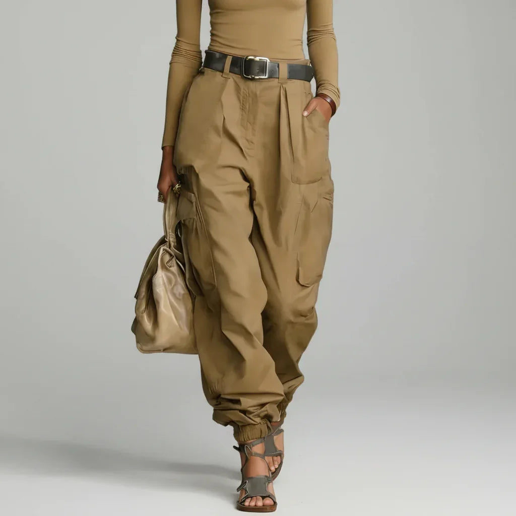 Modelo de calça cargo wide leg caqui de cintura alta com cinto marrom, blusa caqui e bolsa bege