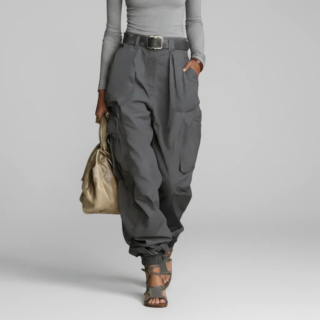 Modelo de calça cargo wide leg cinza chumbo de cintura alta com cinto, blusa cinza clara e bolsa bege