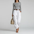 Modelo de calça cargo wide leg branca de cintura alta com cinto marrom, blusa cinza e bolsa bege