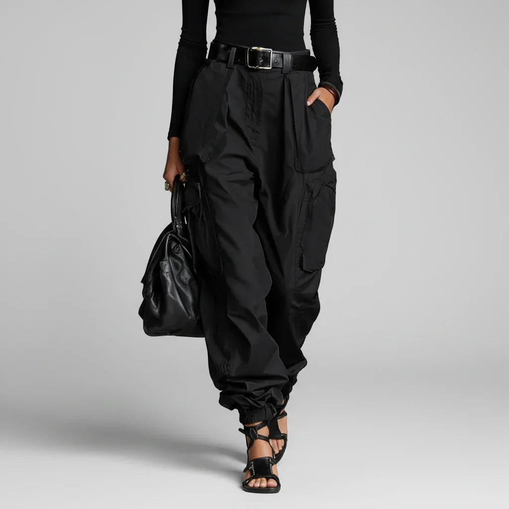 Modelo de calça cargo wide leg preta de cintura alta com cinto e blusa preta, com bolsa preta